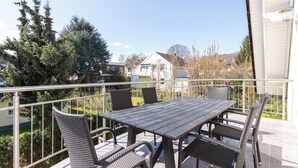 An outdoor balcony with a table and chairs, overlooking a residential area with houses and trees. - 90 sqm Cozy home cinema with balcony & projector (Kassel)