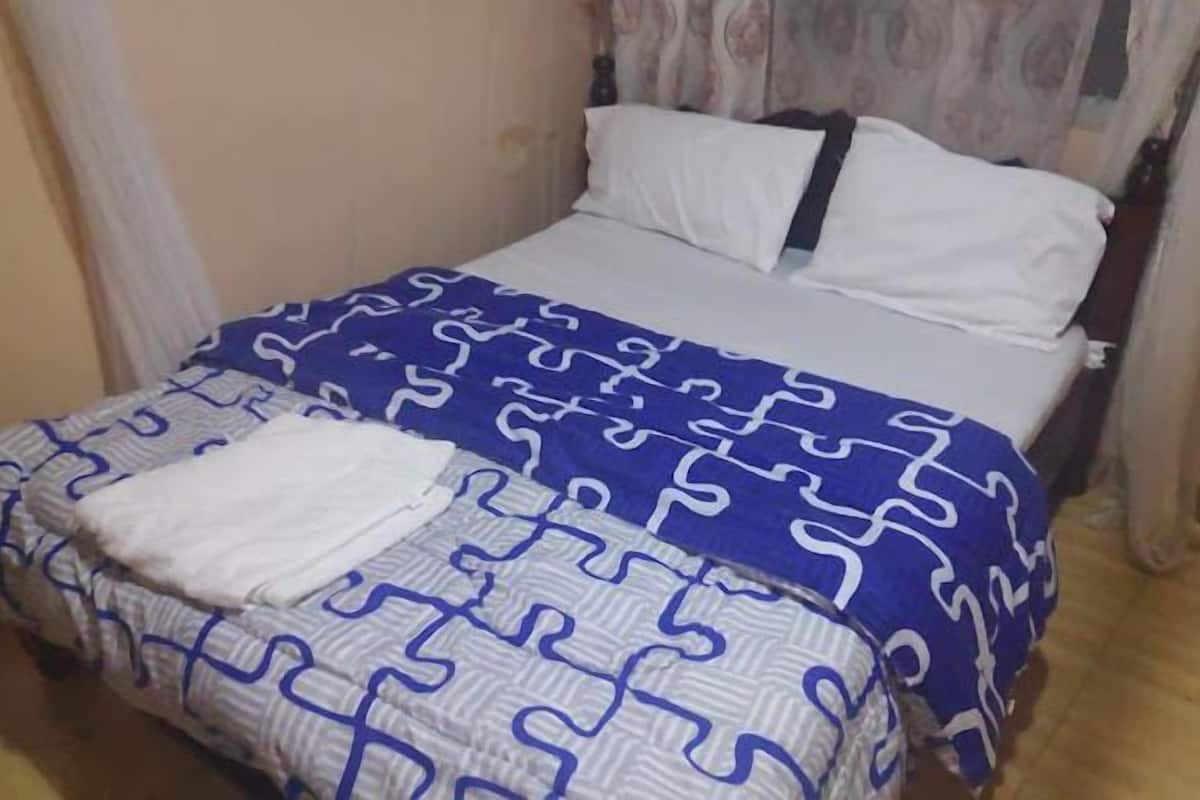 A bed with a patterned bedspread, a white pillow, and a white blanket.