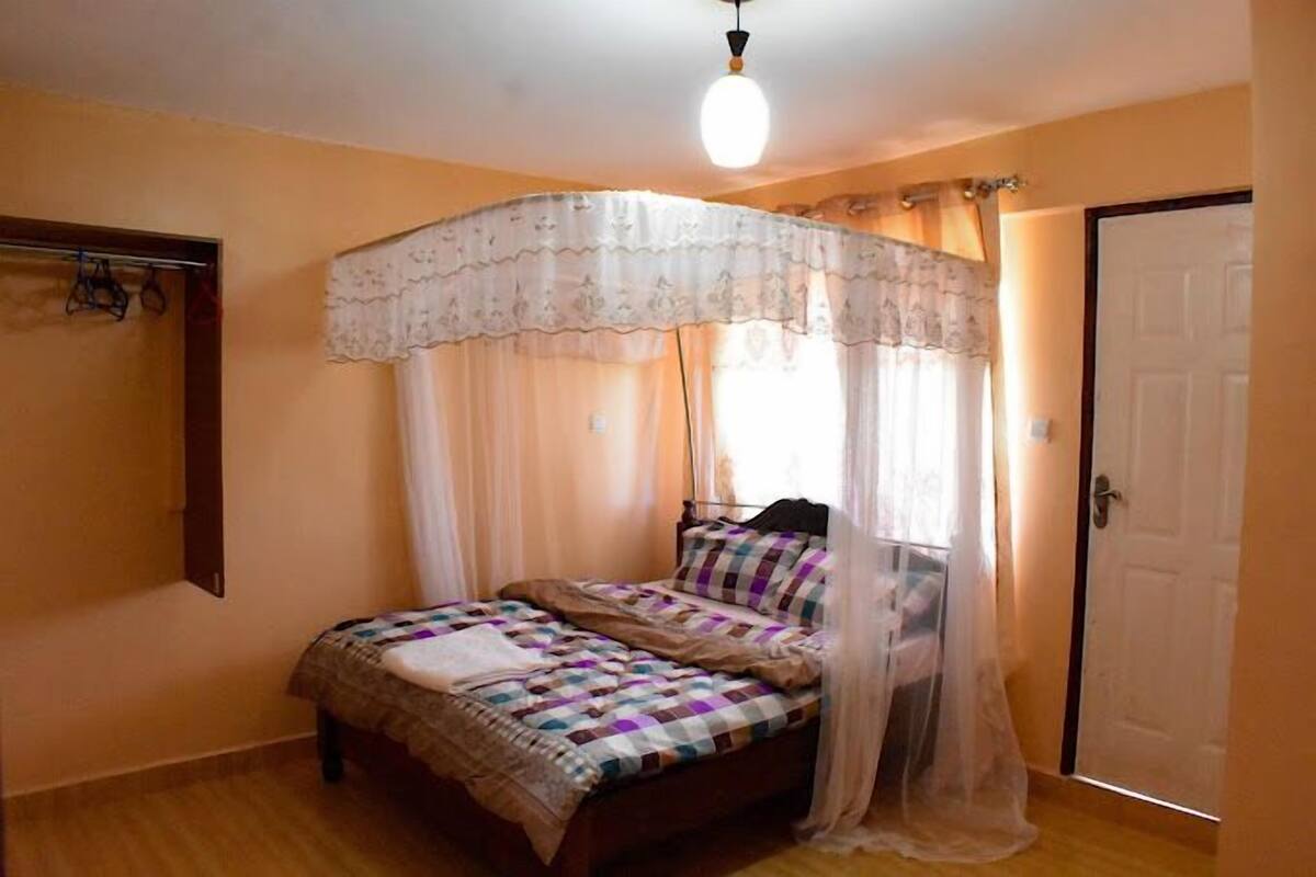 A bedroom with a bed, a canopy, a wardrobe, and a door.