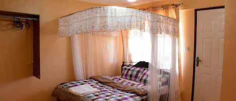 A bedroom with a bed, a canopy, a wardrobe, and a door.