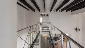 A modern interior with a glass staircase, white walls, and exposed wooden beams. - Appartamento Sammartino by Wonderful Italy (Palermo)