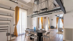 A modern interior with a staircase, a dining area with a round table and chairs, and a view of the living area. - Appartamento Sammartino by Wonderful Italy (Palermo)