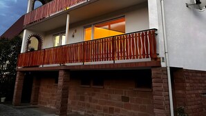 Un edificio de dos pisos con balcón, cimientos de ladrillo y una ventana visible.