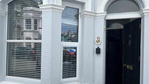 A house with a black door, white window frames, and a number plaque on the wall. - Traditional Victorian house (Hastings)
