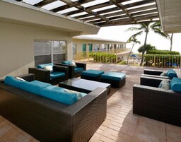Un patio exterior con mobiliario de mimbre y una zona cubierta.