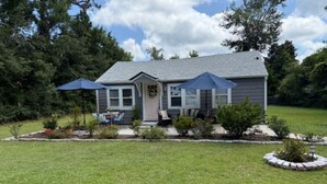 A single-story house with a front porch, a small garden, and a lawn. - Storybook Chatham (Newport)