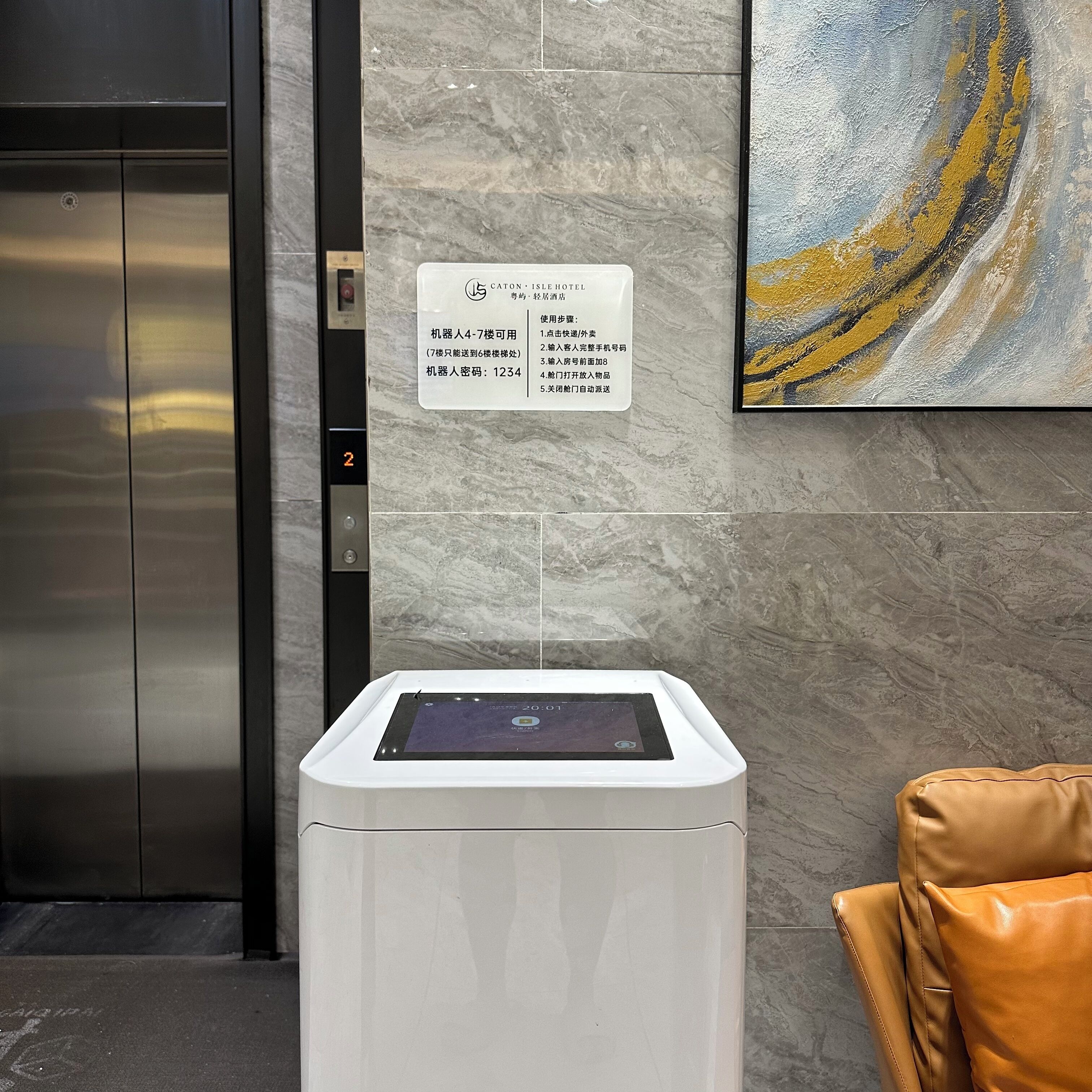 Um elevador com painel digital, parede de mármore e placa com informações do hotel.