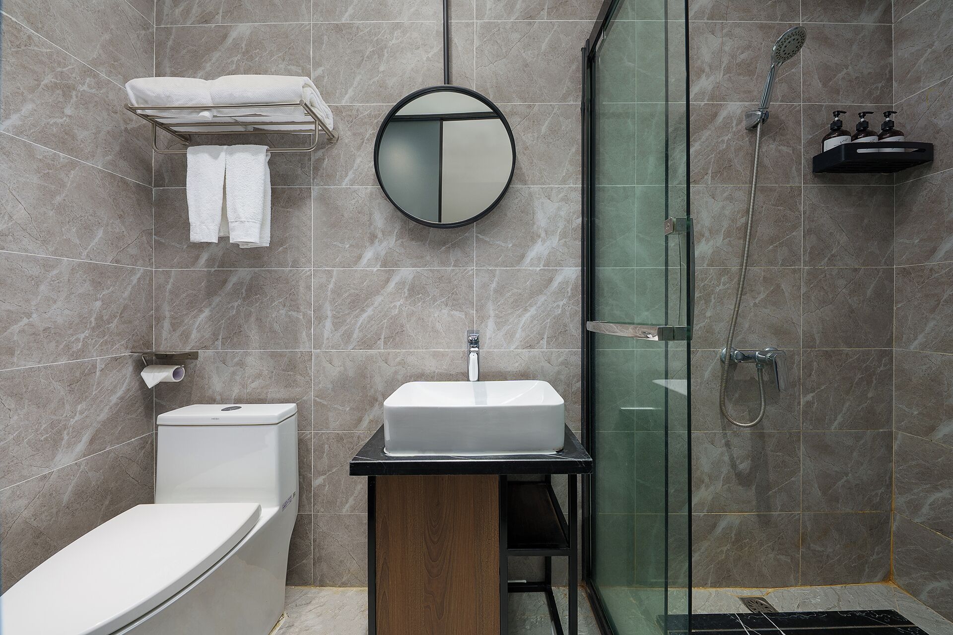 A modern bathroom with a toilet, sink, and glass-enclosed shower.