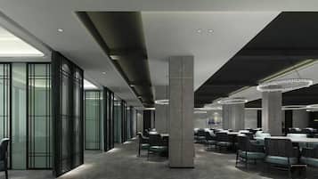 Un salón de conferencias moderno con divisiones de vidrio, techo alto con iluminación empotrada y una araña.