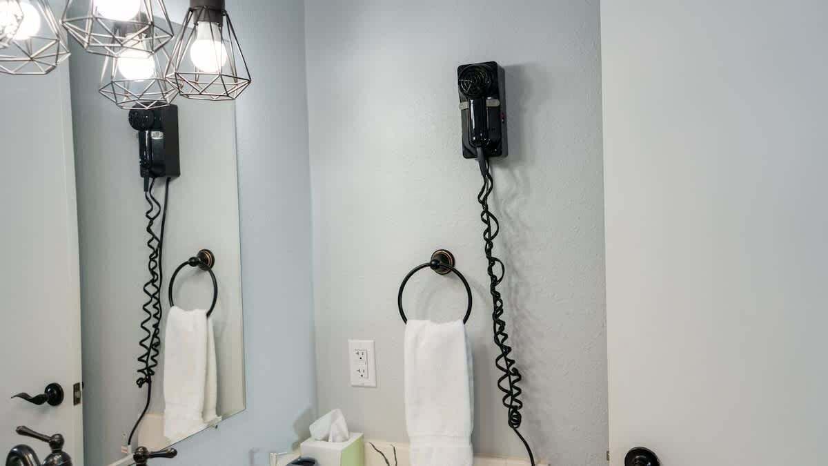Een badkamer met een spiegel, handdoekhouder en een aan de muur bevestigde haardroger.