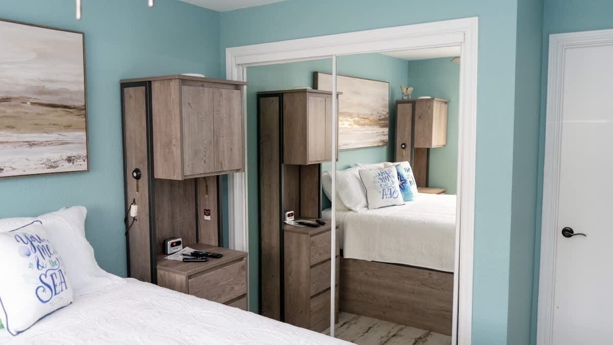 A bedroom with two beds, wooden wardrobes, and a white door.
