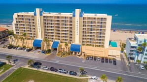 Ein mehrgeschossiges Hotel mit Innenhof, Parkplatz und Blick auf den Strand.