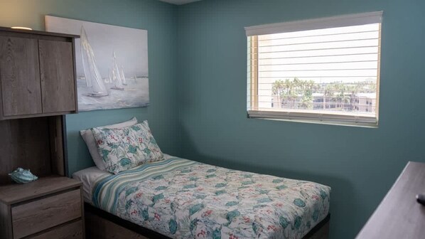 A bedroom with a bed, a nightstand, a dresser, a window with blinds, and a painting of sailboats. - Inverness #505 2 Bedroom Home (South Padre Island)