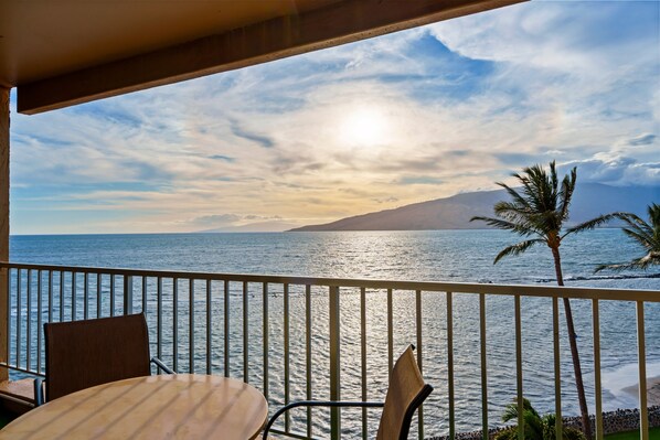 Un balcon avec vue sur l’océan et une montagne qui se profile à l’horizon.