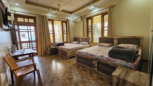 A room with two wooden beds, a wooden table, and a chair. - Bora's Homestay (Haldwani)