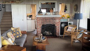 A cozy living room with a fireplace, a staircase, and a dining area.
