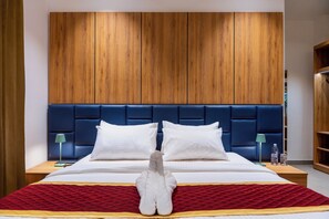 Una cama bien hecha con sábanas blancas, una colcha acolchada roja y un objeto decorativo blanco en el centro.