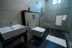 A modern bathroom with a sink, toilet, and glass-enclosed shower. - Nes-Terns (Coimbatore)