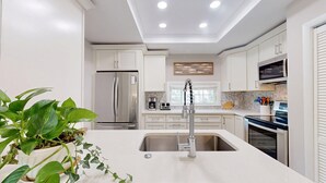 A modern kitchen with white cabinetry, stainless steel appliances, and a central island with a sink. - Private home in Hilton Head Island with a private pool and hot tub! (Hilton Head)