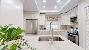 Una cocina moderna con armarios blancos, electrodomésticos de acero inoxidable y una isla central con pileta.