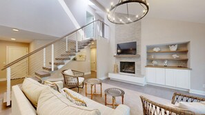 Een ruime woonkamer met trap, open haard, televisie en boekenkast.