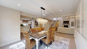 A spacious dining area with a high ceiling, a modern chandelier, and a staircase leading to an upper level. - Private home in Hilton Head Island with a private pool and hot tub! (Hilton Head)