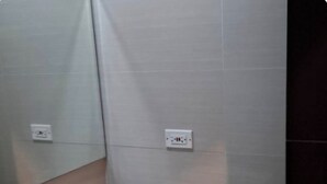 Ein Badezimmer mit einem weißen Waschbecken, einem Spiegel und zwei Steckdosen an der Wand.