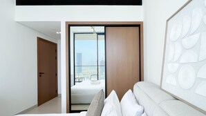 A modern hotel room with a large bed, a city view, and a unique wall art piece. - Luxury & Comfort 1B at Binghatti Amber & Balcony (Dubai)