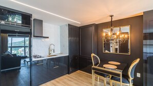 A modern kitchen with dark cabinetry, a black dining table, and a chandelier.