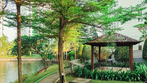 Un parque tranquilo con un estanque, un pabellón y un sendero.