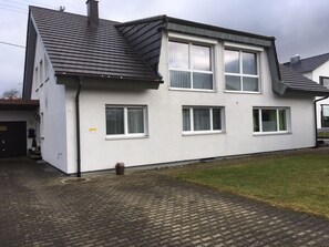 Een gebouw met twee verdiepingen, een plat dak en een geplaveid oprit.