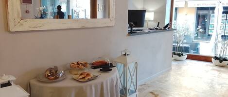 Una habitación con una mesa de comedor dispuesta con comida, un espejo grande y vista a la calle.