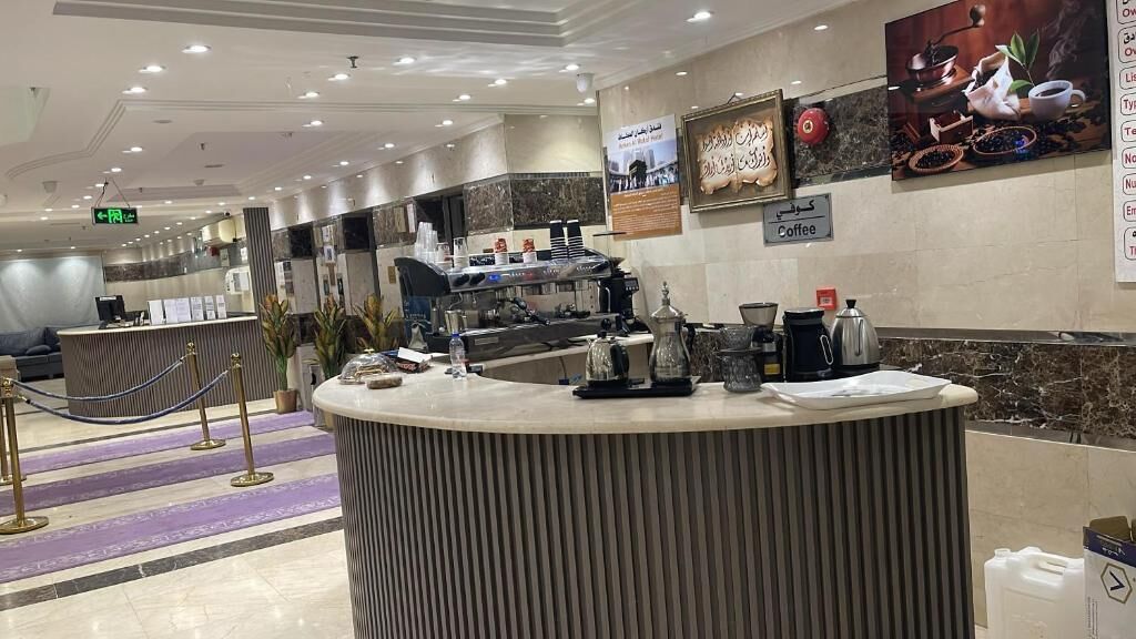Ein Hotel-Rezeptionsbereich mit Empfangstresen, einer Kaffeestation und einem Schild, das einen Kaffeeservice anzeigt.