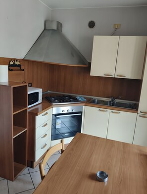 Una cucina dotata di microonde, fornello, forno e mobili in legno.