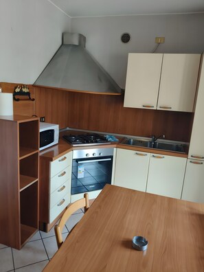 Una cocina compacta con microondas, estufa, horno y armarios de madera.