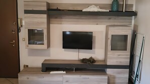 Un salon moderne avec un téléviseur à écran plat fixé à un mur en bois, un banc intégré avec espace de rangement et un sol carrelé.