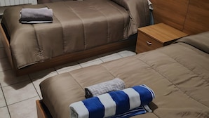 Une chambre d’hôtel avec deux lits, une tête de lit en bois, une table de chevet et un radiateur.