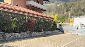 Un bâtiment doté d’un toit en tuiles, d’un balcon et d’une zone pavée agrémentée d’un jardinière.