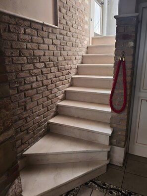 A staircase with beige steps, a brick wall, and a red rope. - Arcadia Apartments Zaffiro: Mountain View, Wi-Fi & Air Conditioning (Carpeneda)
