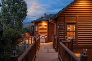 A wooden cabin with a wooden deck leading to a covered porch area. - Luxury Log Cabin | Panoramic Views, Game Room, 2 Fireplaces & Outdoor Kitchen (Big Bear City)