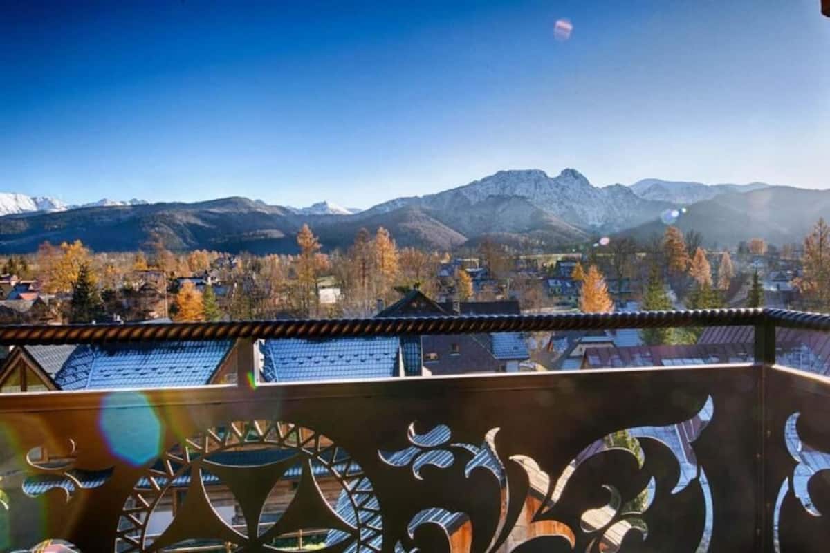 A balcony with a view of a mountainous landscape, a clear sky, and a sun setting or rising.