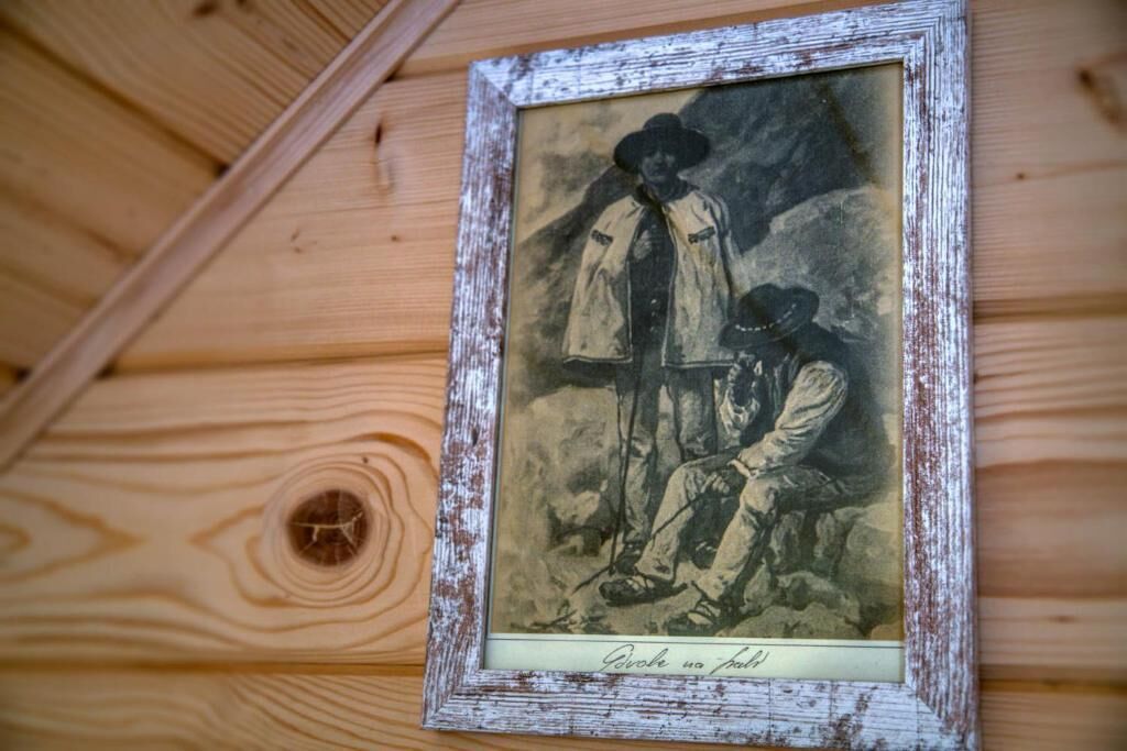 A framed historical photograph with a caption, mounted on a wooden wall with a circular window.