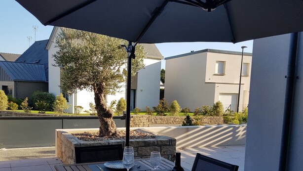 An outdoor dining area with tables, chairs, and umbrellas. - Modern holiday home with private terrace, Wi-Fi, and air conditioning (Fouesnant)