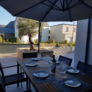 Un'area pranzo all'aperto con tavoli, sedie e ombrelloni.