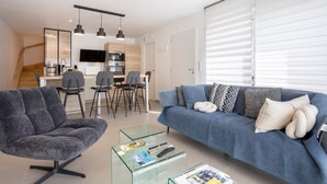 A modern living room with a sofa, armchair, and glass coffee table. - Modern holiday home with private terrace, Wi-Fi, and air conditioning (Fouesnant)