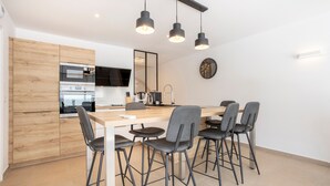 A modern kitchen with a wooden countertop, a built-in oven, and a dining area with a wooden table and four chairs. - Holiday Home 'Korñog Near the Beach' with Private Terrace, Wi-Fi and Air Conditioning (Fouesnant)