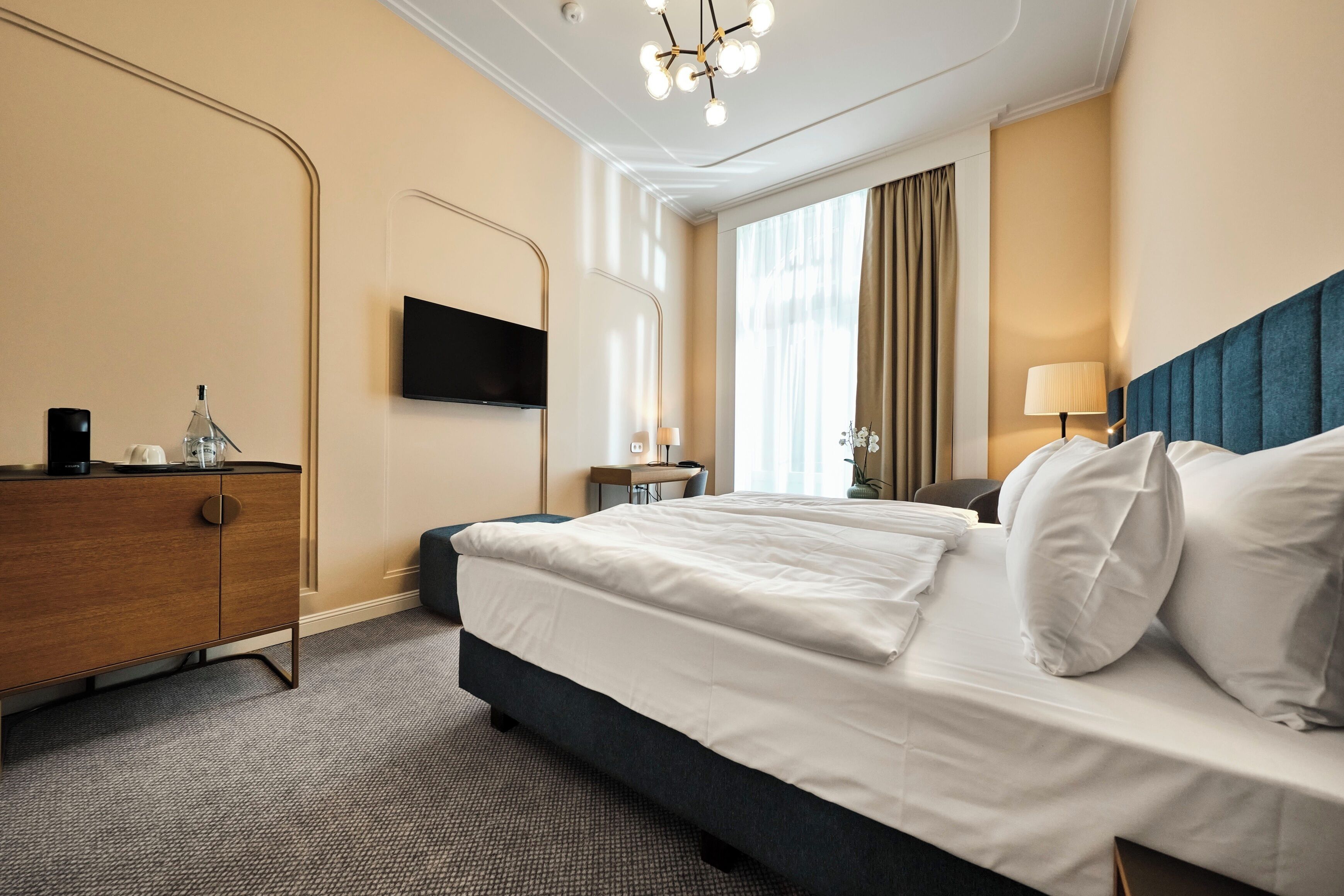 Una camera d'albergo con un letto, una scrivania, una televisione e un armadio.