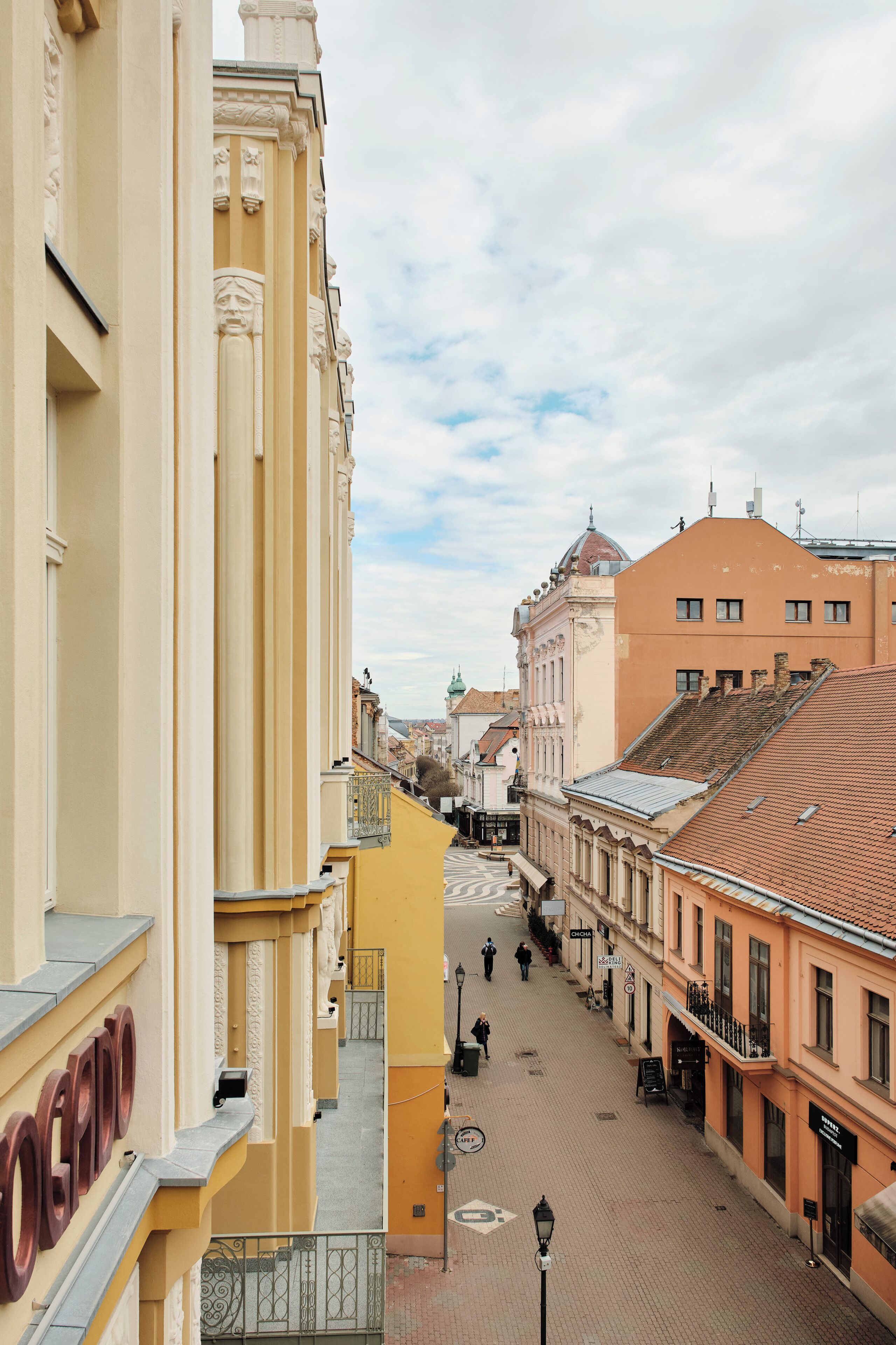 A street view with buildings, a clear sky, and a pedestrian walkway.