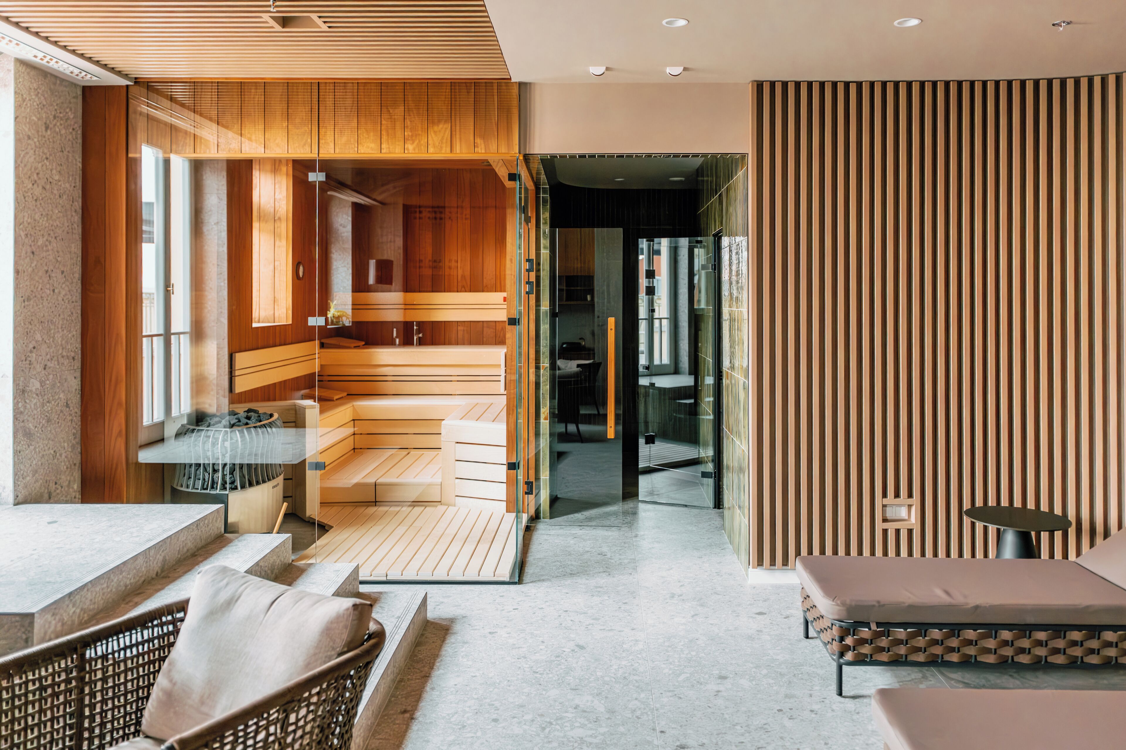 A modern spa area with wooden flooring, a sauna, and a glass-enclosed relaxation area.