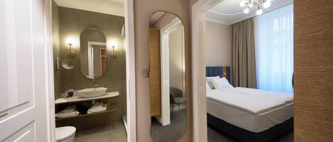 A hotel room with a bathroom, a bed, and a large mirror.